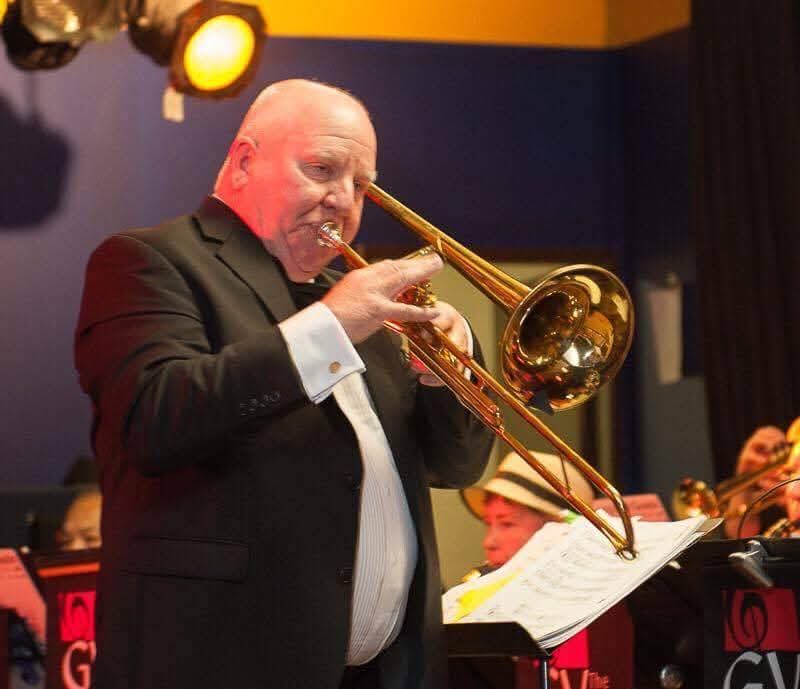Keith Fraser playing trombone on stage with a band